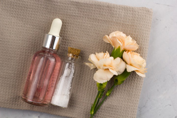 aroma oil  sea salt bottles fresh flowers on towel marble table top view spa welness concept