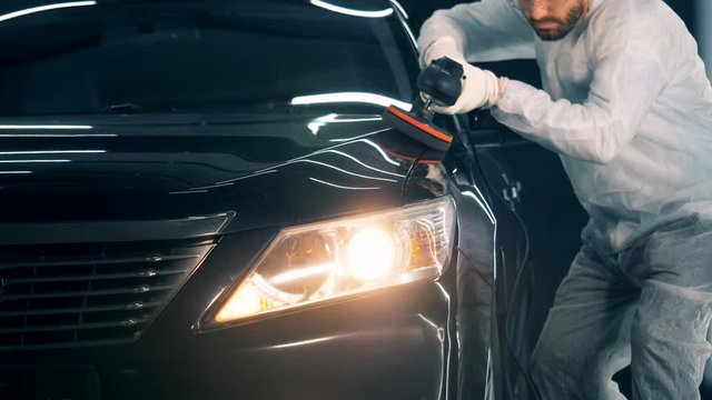 Person uses polishing equipment while working in a car service. 4K
