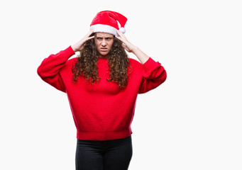 Young brunette girl wearing christmas hat over isolated background suffering from headache desperate and stressed because pain and migraine. Hands on head.