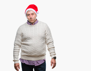 Handsome senior man wearing christmas hat over isolated background puffing cheeks with funny face. Mouth inflated with air, crazy expression.