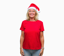 Middle age blonde woman wearing christmas hat over isolated background with a happy and cool smile on face. Lucky person.