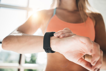 Fitness woman after workout session checks results on smartwatch in fitness app. Healthy lifestyle concept. Female athlete wearing sport tracker wristband arm