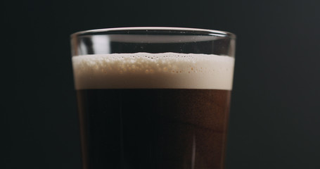 Closeup dark stout beer with bubbles over black background