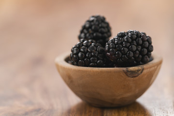 fresh blackberries in wood bowl on wooden table