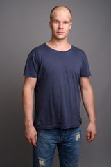Fototapeta premium Bald man wearing blue shirt against gray background