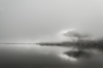 Fototapeta premium Early foggy wet morning on the lake between the mountains in Austrian Alps
