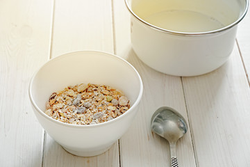 healthy breakfast muesli with snacks, white bowl and spoon on white wood background