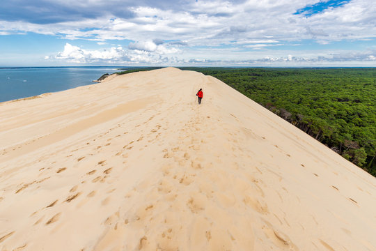 Woman walking on large sand dune