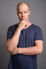 Bald man wearing blue shirt against gray background