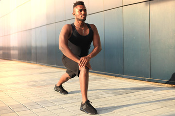 African man in sports clothing warming up outdoors, at sunset or sunrise. © ty