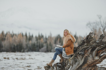 Beautiful girl in fur clothes with book and a hood in winter