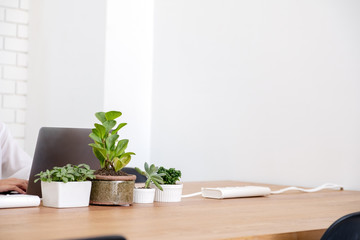 Closeup image of hands using and typing on laptop keyboard on wooden table in office