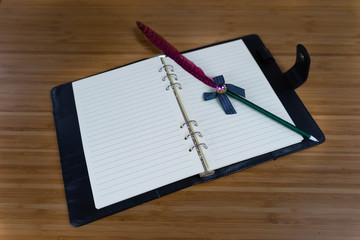 Hand writing books wallet and notebook placed on a wooden table. top view image of open notebook with blank pages next to cup of coffee on wooden table. Notepad with pencil on the wood background.