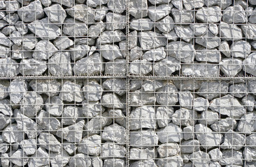 The texture of the wall of small gray stones under iron mesh. Natural stone wall texture photo, stone background , stone floor texture, grey floor in the garden, grey wall background.