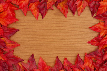 Naklejka na ściany i meble Autumn background with red and orange fall leaves on wood