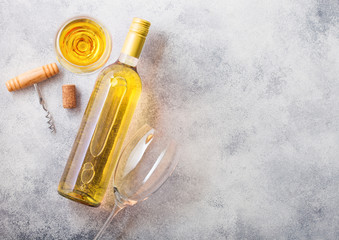 Bottle and glasses of white wine with cork and crkscrew opener on stone kitchen table background....
