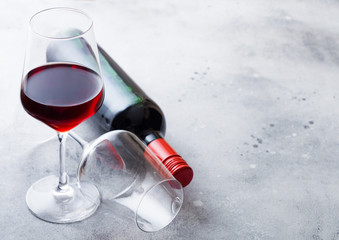 Elegant glass and bottle of red wine on stone kitchen table background. Space for text
