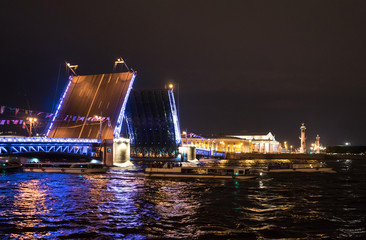 Fototapeta na wymiar Divorced Palace Bridge, the Spit of Vasilyevsky Island and boats under the bridge at night in St. Petersburg. Russia