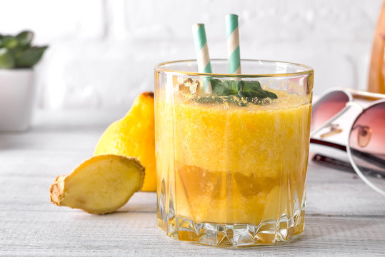 Yellow banana smoothie with mint decorated with a small brunch of green french minton wooden white background.