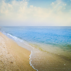 Blue sea, sky and beach with footprints in the sand
