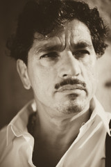 Portrait of a man with an interesting face typical of southern Italy, that can be defined both handsome or ugly, with black hair, moustaches, white skirt.