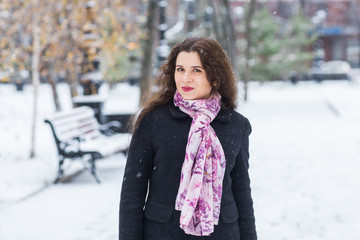 Side portrait of woman is taking a walk outdoors in winter park