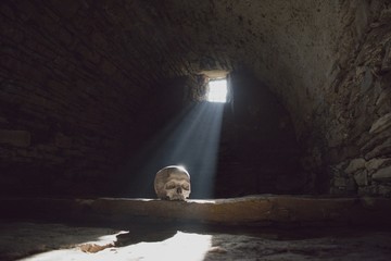 Human skull in the scary underground, spooky old castle cellar