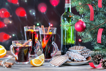Christmas mulled red wine with spices and cookies on a wooden rustic table with fir branches. Traditional hot drink at Christmas time