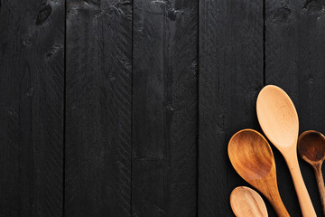 Wooden spoons on black wooden background with copy space. Top view of various types of wooden...