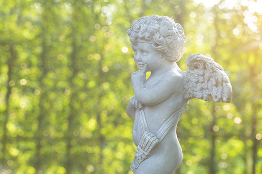 Cupid sculpture on green background in the garden