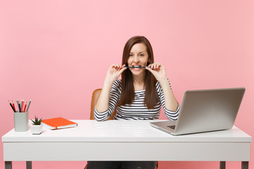 Passionate woman in casual clothes gnawing hold pencil in teeth sit work at white desk with...