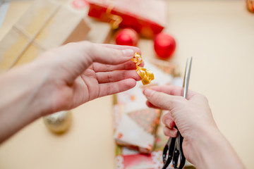 Female hands holding presents and packing presents. Presents and christmas balls, holiday concept. Red, green and golden paper.