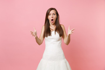 Portrait of angry shocked bride woman with opened mouth in white wedding dress standing spreading...