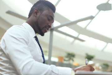 Portrait of successful African-American businessman sitting at desk with computer in office.