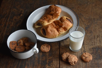 Plato con napolitanas de chocolate, vaso de leche y galletas