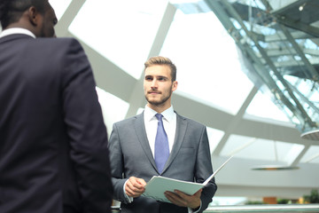 Two multinational young businessmen discussing business at meeting in office.