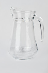 Empty glass jug isolated. Glass jug with handle on light background. Glass ware for milk.