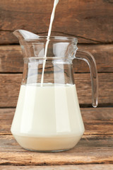 Milk pouring into a jug. Filling a glass pitcher with fresh milk. Eco milk concept.