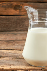 Cow milk in jug, cropped image. Fresh milk in glass pitcher on retro wooden background. Healthy eating concept.