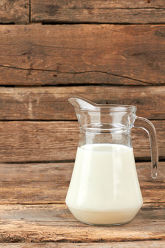 Organic milk in glass jug. Natural cow milk in glass pitcher on rustic wooden boards. Health benefits of milk.
