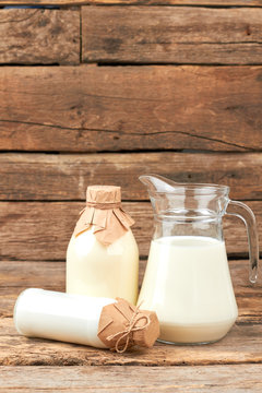 Cow milk in vintage style bottles. Milk in pitcher and bottle. Sour cream in bottle on wooden boards. Keto diet and dairy.