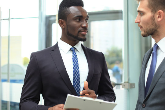 Two Multinational Young Businessmen Discussing Business At Meeting In Office.