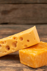 Two pieces of fresh cheese. Tasty cheese on rustic wooden background. Delicious dairy product.