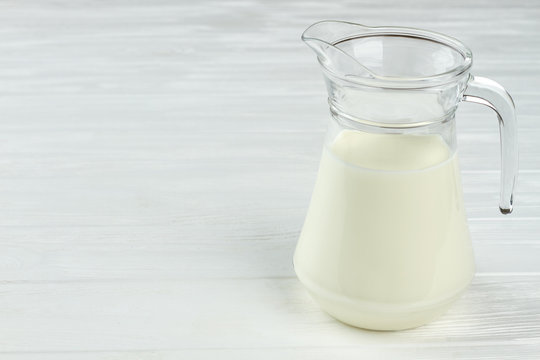 Milk in glass pitcher and copy space. Fresh white milk in glass jar on light background and text space. Eco dairy food.