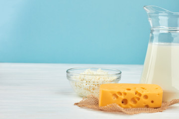Fresh dairy products background. Chunk of swiss cheese and jug with milk. Cottage cheese in glass bowl. Healthy milk food.