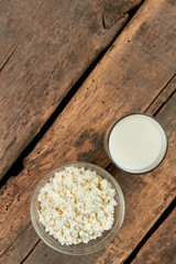 Dairy products on wooden boards. Cottage cheese and cup of fresh milk on rustic wooden planks, top view. Natural eating concept.