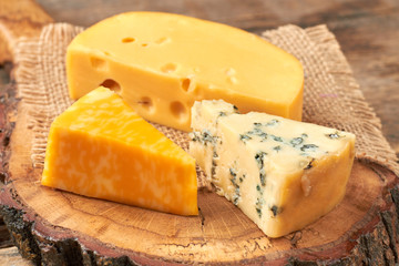 Cheese set on wooden board. Variety of delicious cheese pieces close up. Rich with nutrients.