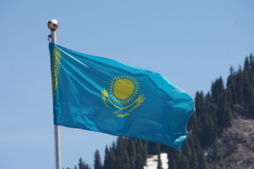 Flag of Kazahstan in blue sky and montain in behind Almaty Medeo