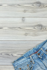 Blue jeans with copy space on top. Light blue denim pants on wooden background, text space. Casual male garment.