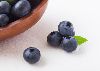 Fresh raw organic blueberries with leaf in wooden bowl on white background. Macro